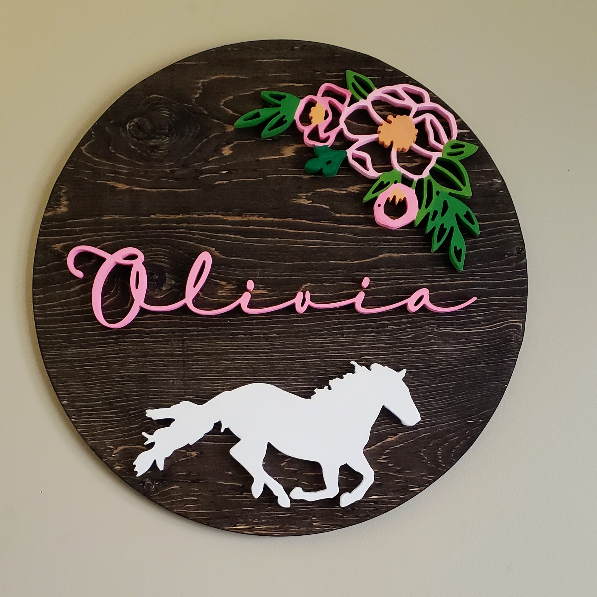 Espresso stained round sign with the name Olivia, pink flowers with greenery above the name and an elegant white horse on the bottom half.